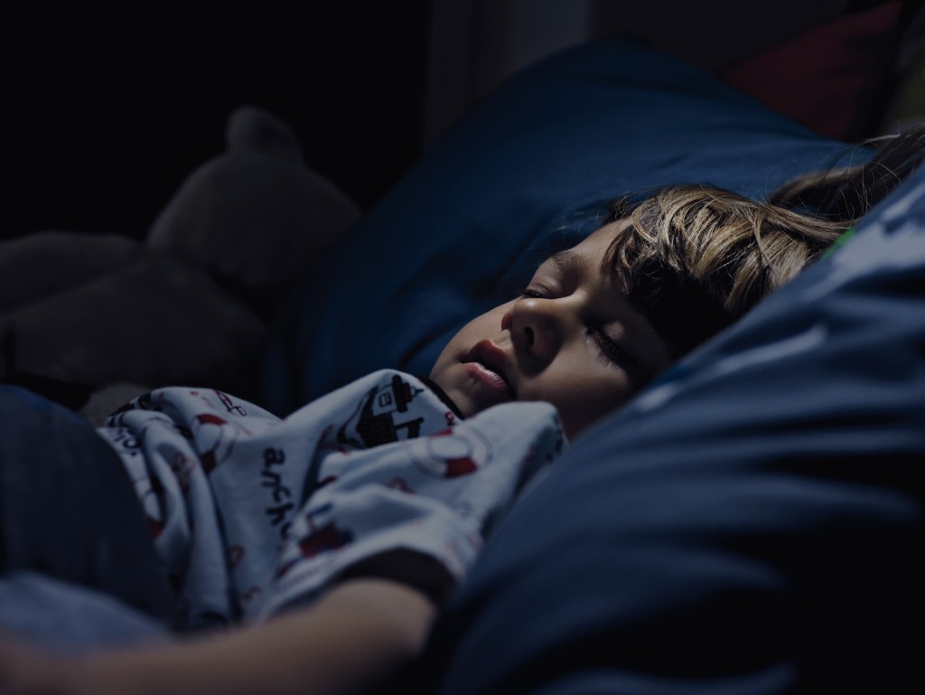 Kleiner Junge schläft in dunklem Raum