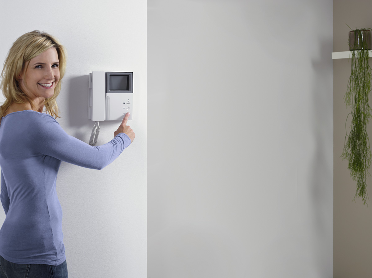 Frau beim Öffnen der Tür über die Gegensprechanlage