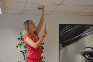 Eine Frau bei der Kontrolle eines Rauchmelders